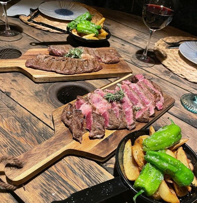 Una mesa de madera cubierta con platos de comida y una copa de vino.