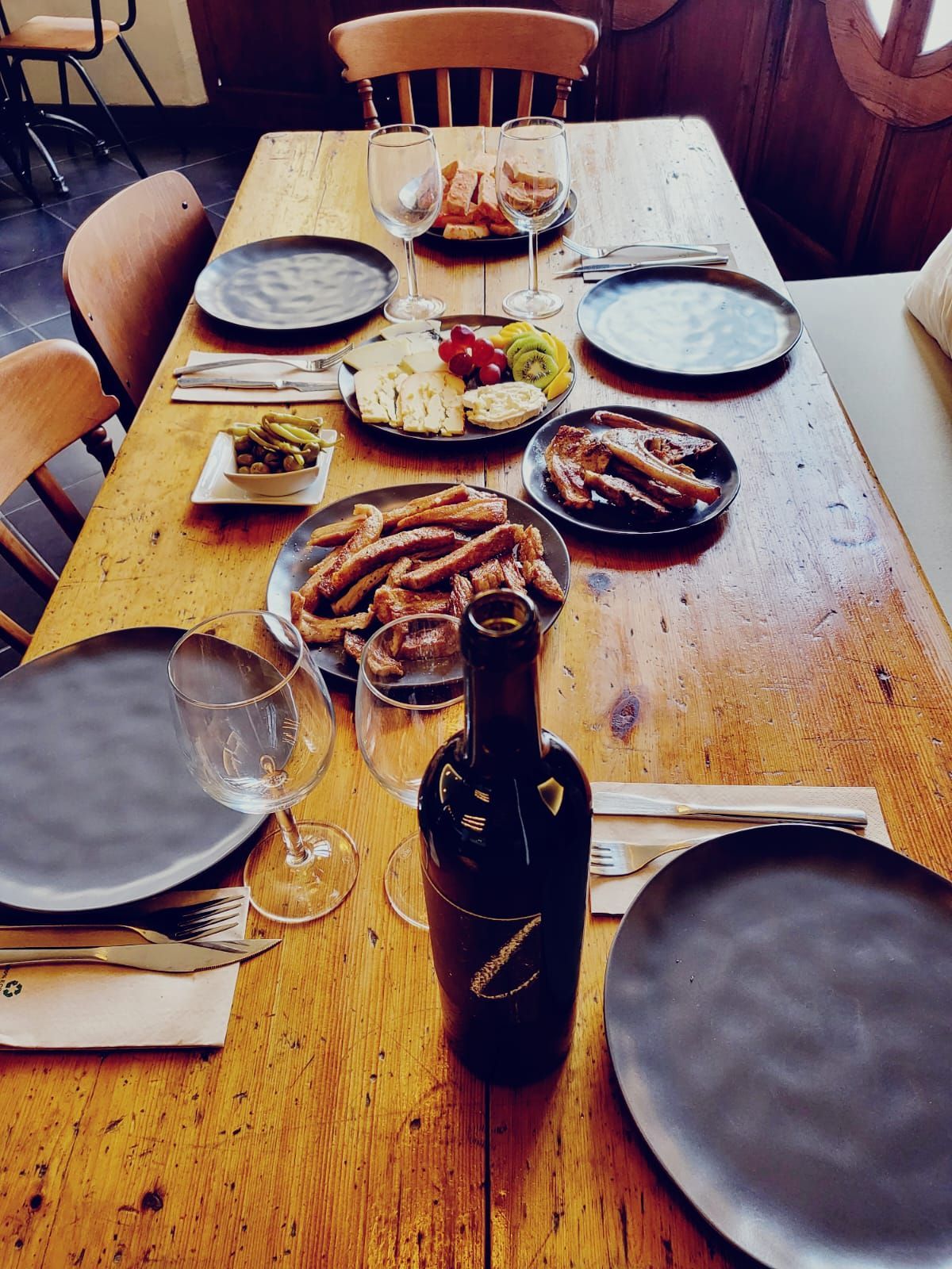 Una mesa de madera con platos y una botella de vino sobre ella.