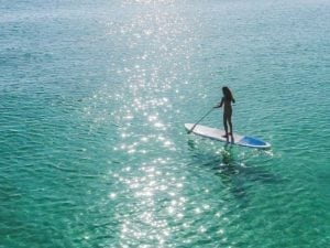 Una mujer está parada sobre una tabla de remo en el océano.
