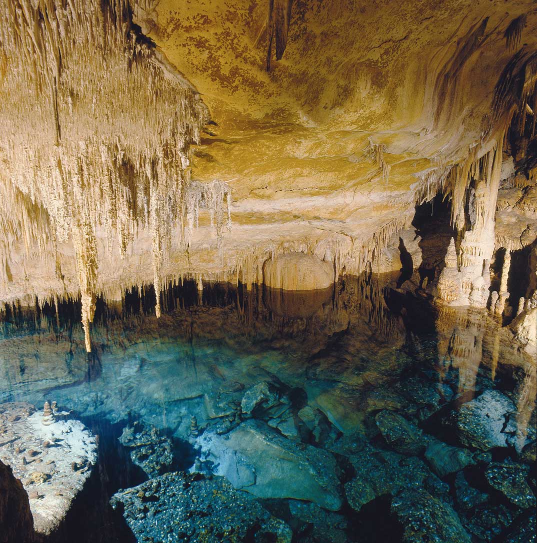 Una cueva con un estanque de agua y muchas rocas.