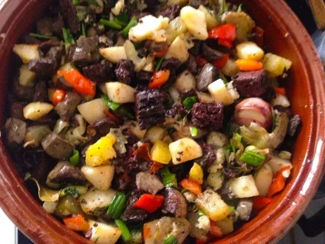 Un recipiente lleno de verduras y carne sobre una estufa.