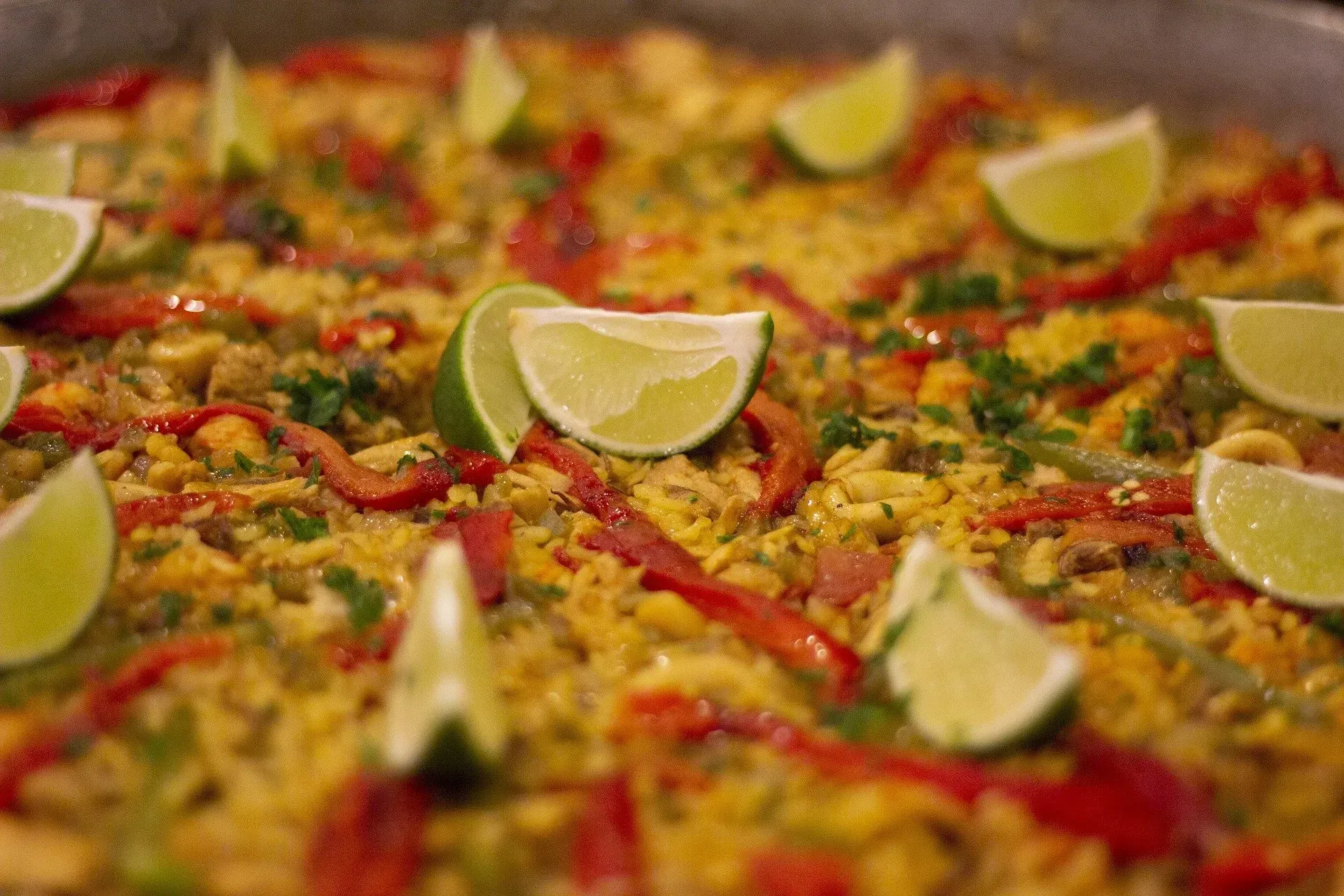 Un primer plano de una paella con rodajas de lima encima.