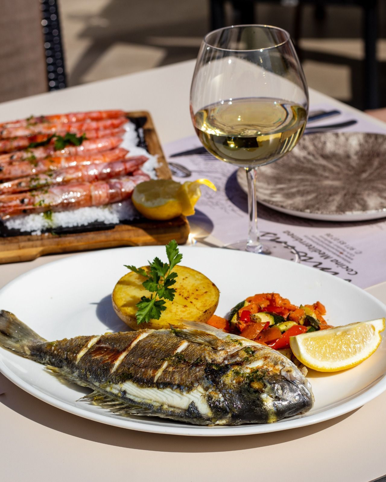 Un plato de comida con una copa de vino en una mesa.