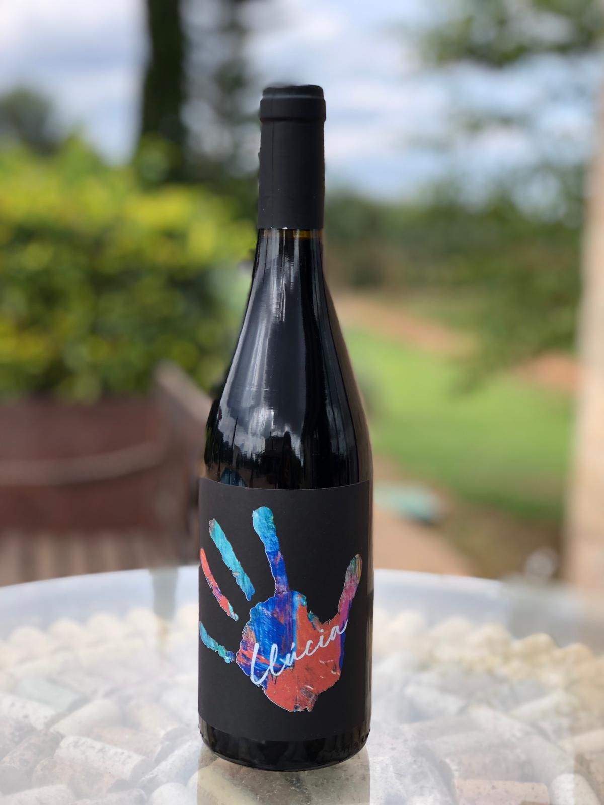 Una botella de vino con una huella de mano en la etiqueta está sobre una mesa.