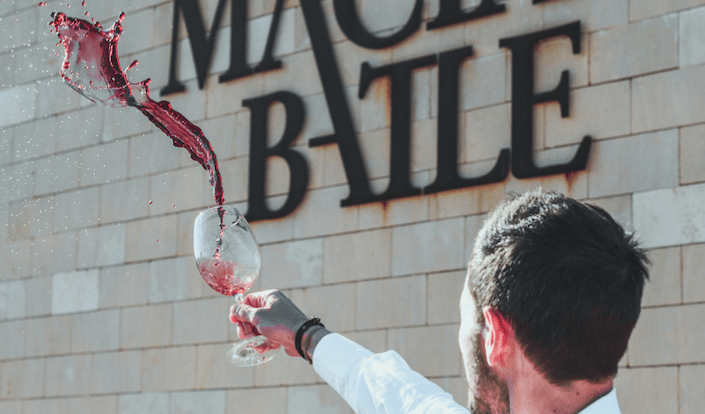 Un hombre está sirviendo vino en un vaso frente a una pared de ladrillos.