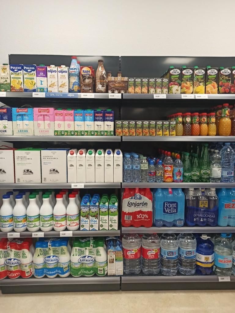 Un pasillo de una tienda de comestibles lleno de leche, jugo y agua.
