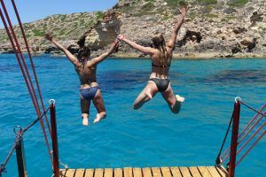 Dos mujeres en bikini saltan al agua.