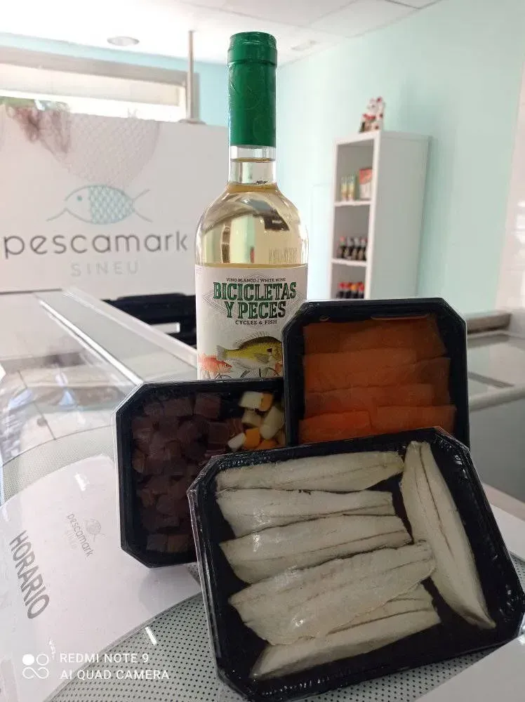 Una botella de vino está junto a una bandeja de comida.