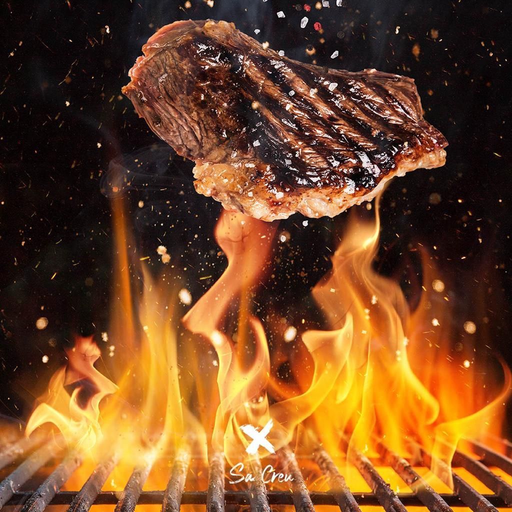 Se está cocinando un filete en una parrilla con llamas.