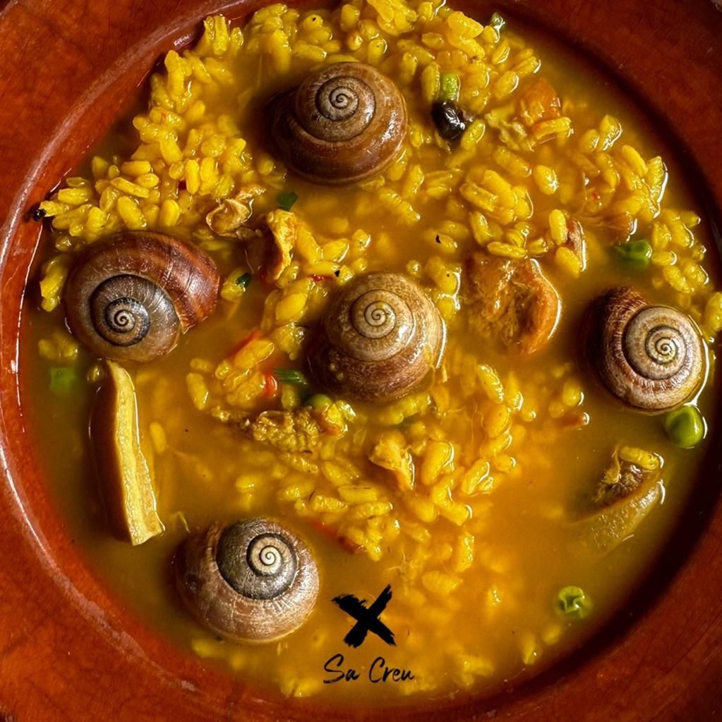 Un primer plano de un cuenco de arroz con caracoles dentro.