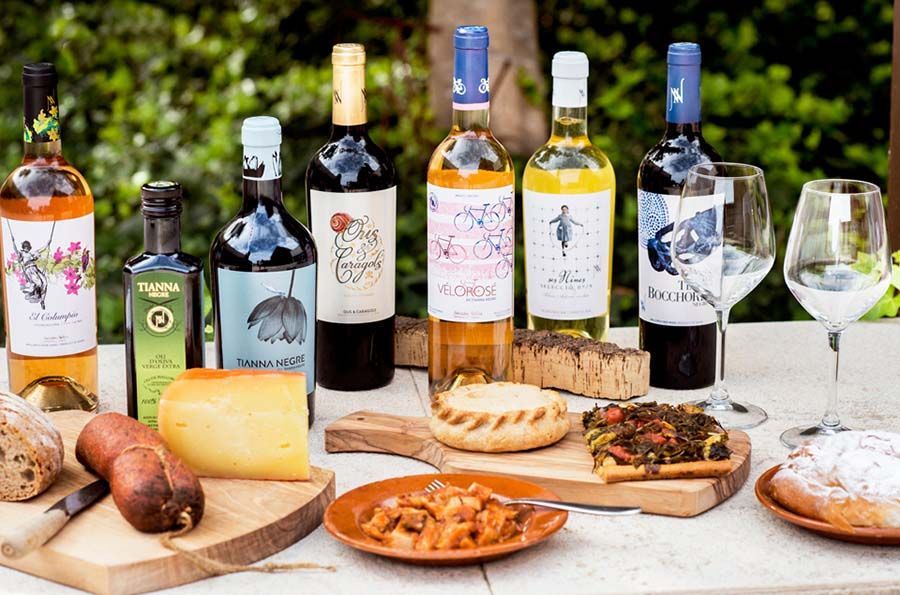 Una mesa repleta de botellas de vino, comida y copas.