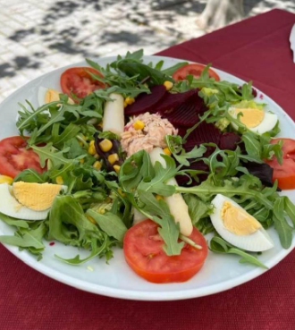 Una ensalada con tomates y huevos en un plato blanco.