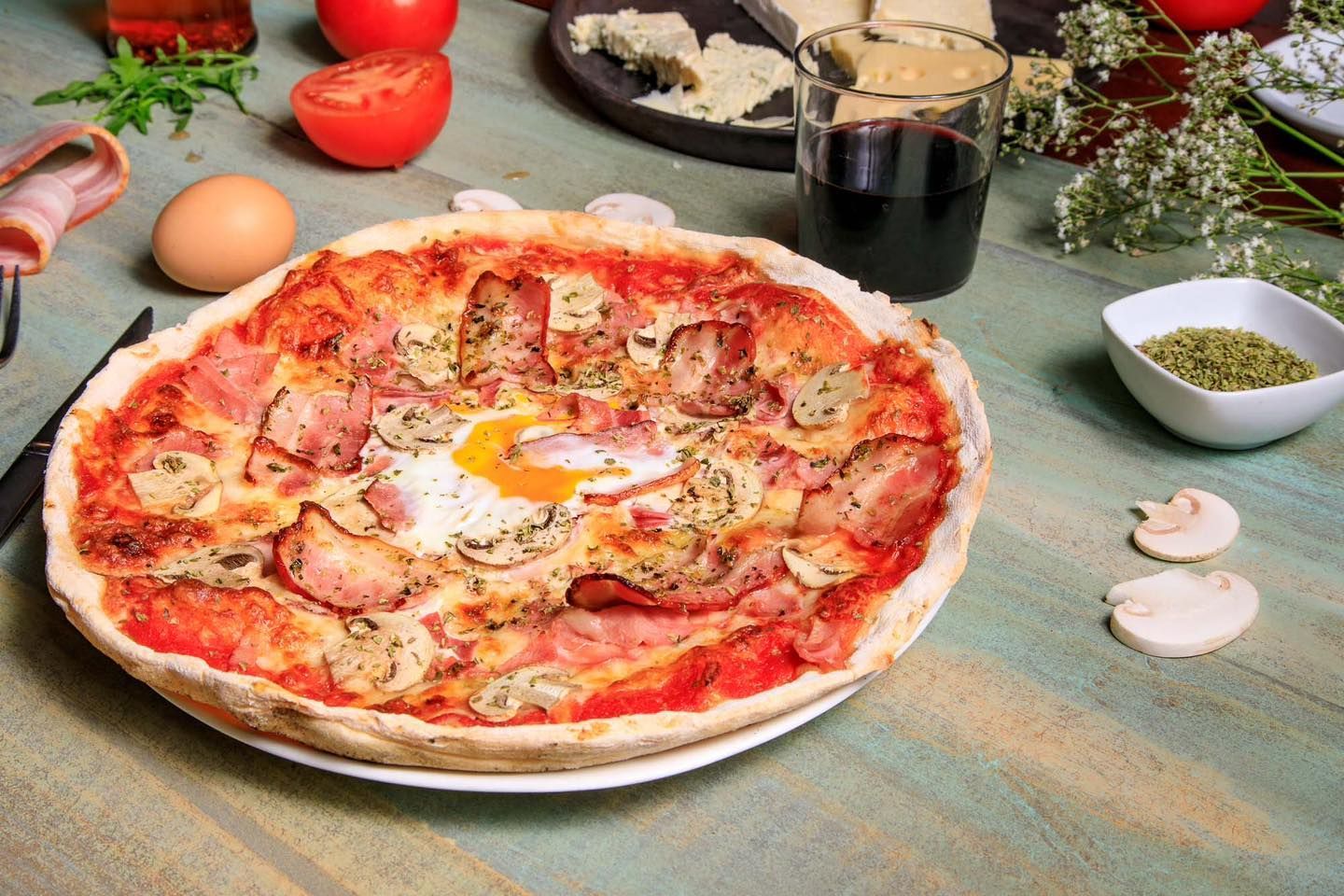 Una pizza con jamón, champiñones y un huevo en un plato sobre una mesa.