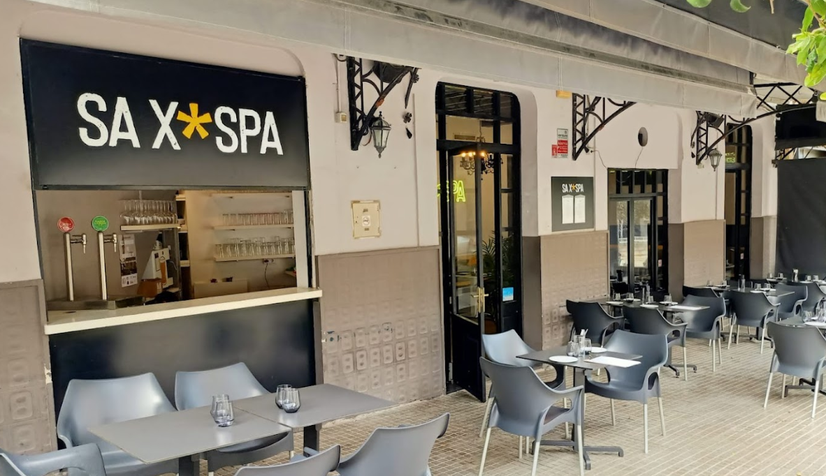Un restaurante con mesas y sillas al aire libre y un cartel que dice sa x spa
