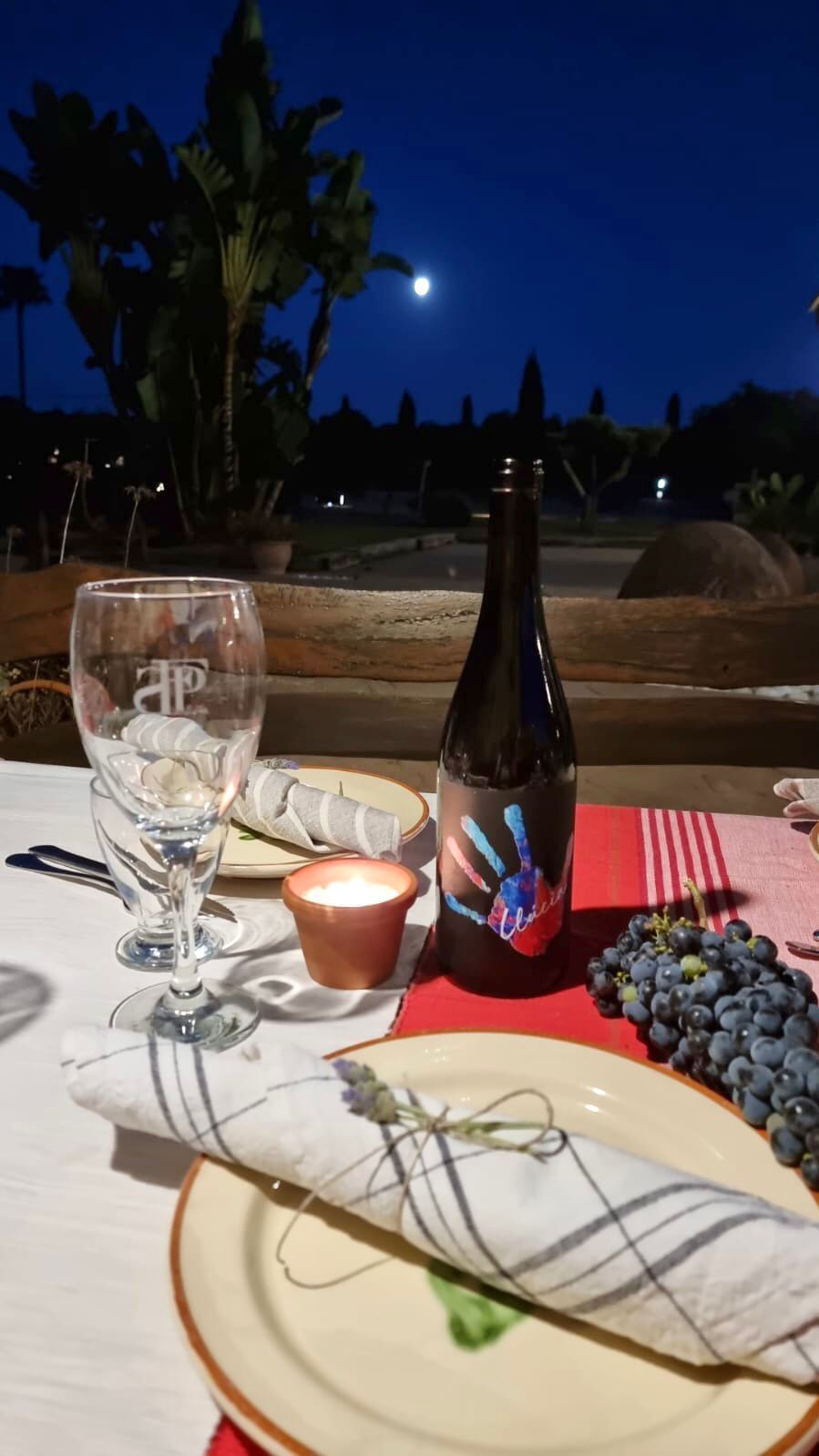 Una botella de vino reposa sobre una mesa con platos y vasos.