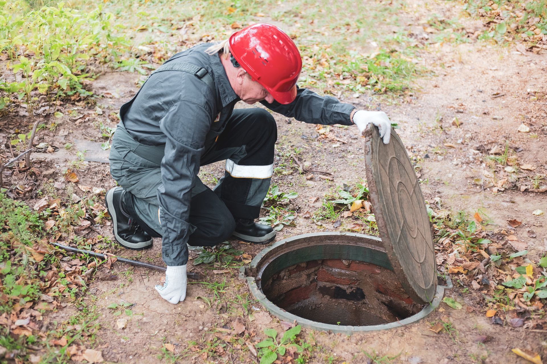 A man is inspecting a septic tank. A man is inspecting a septic tank.