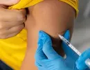 Healthcare worker administering a shot in a patient’s upper arm with a syringe and blue gloves