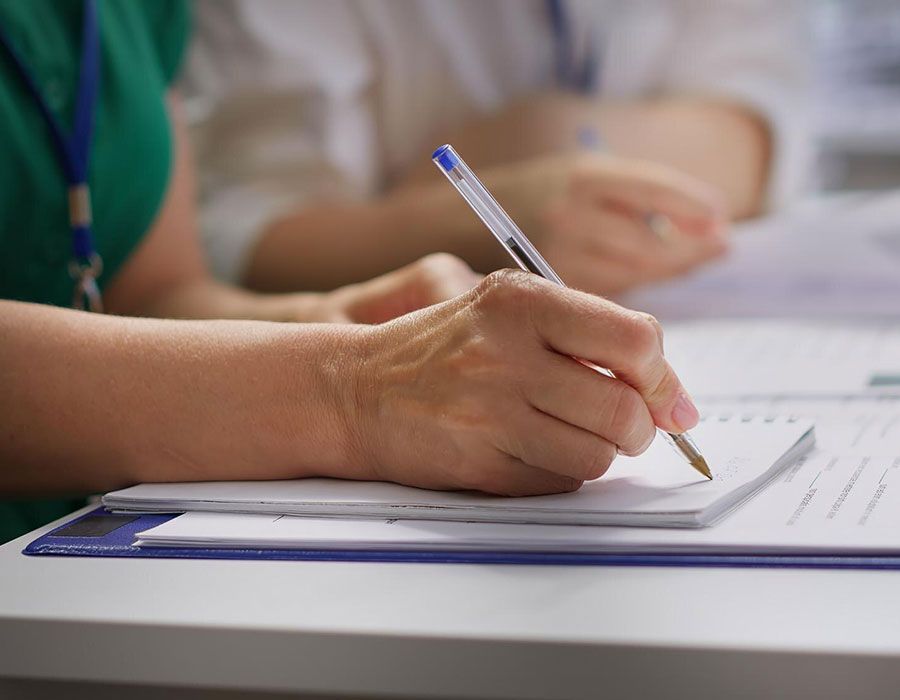 Hand writing with a pen on a paper form at a desk