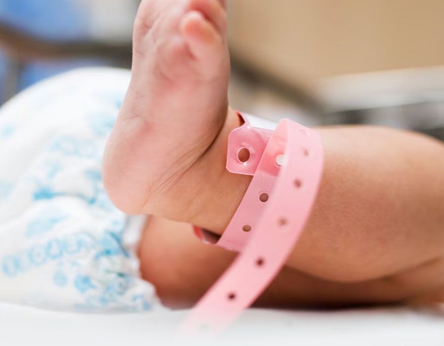 Baby’s feet with a pink hospital ID bracelet