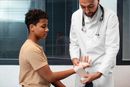 Doctor wrapping a boy’s wrist in a clinic exam room