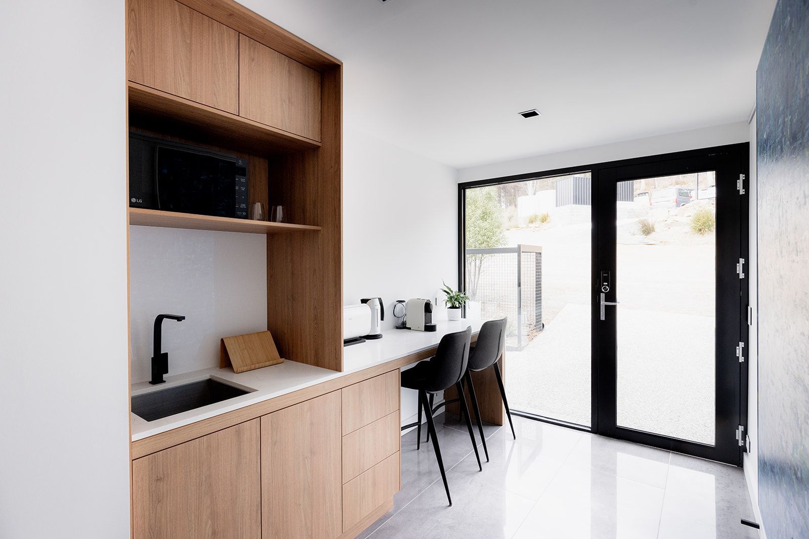 A kitchen with a sink , microwave , and chairs.