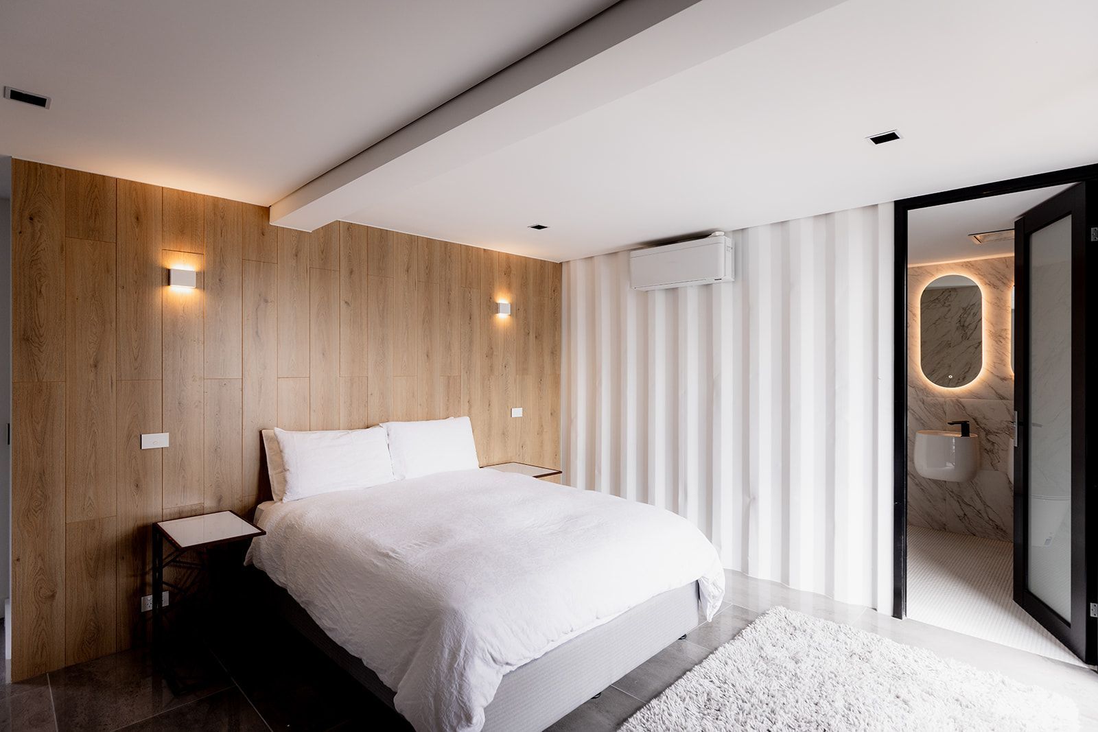 A bedroom with a large bed and a bathroom in the background.