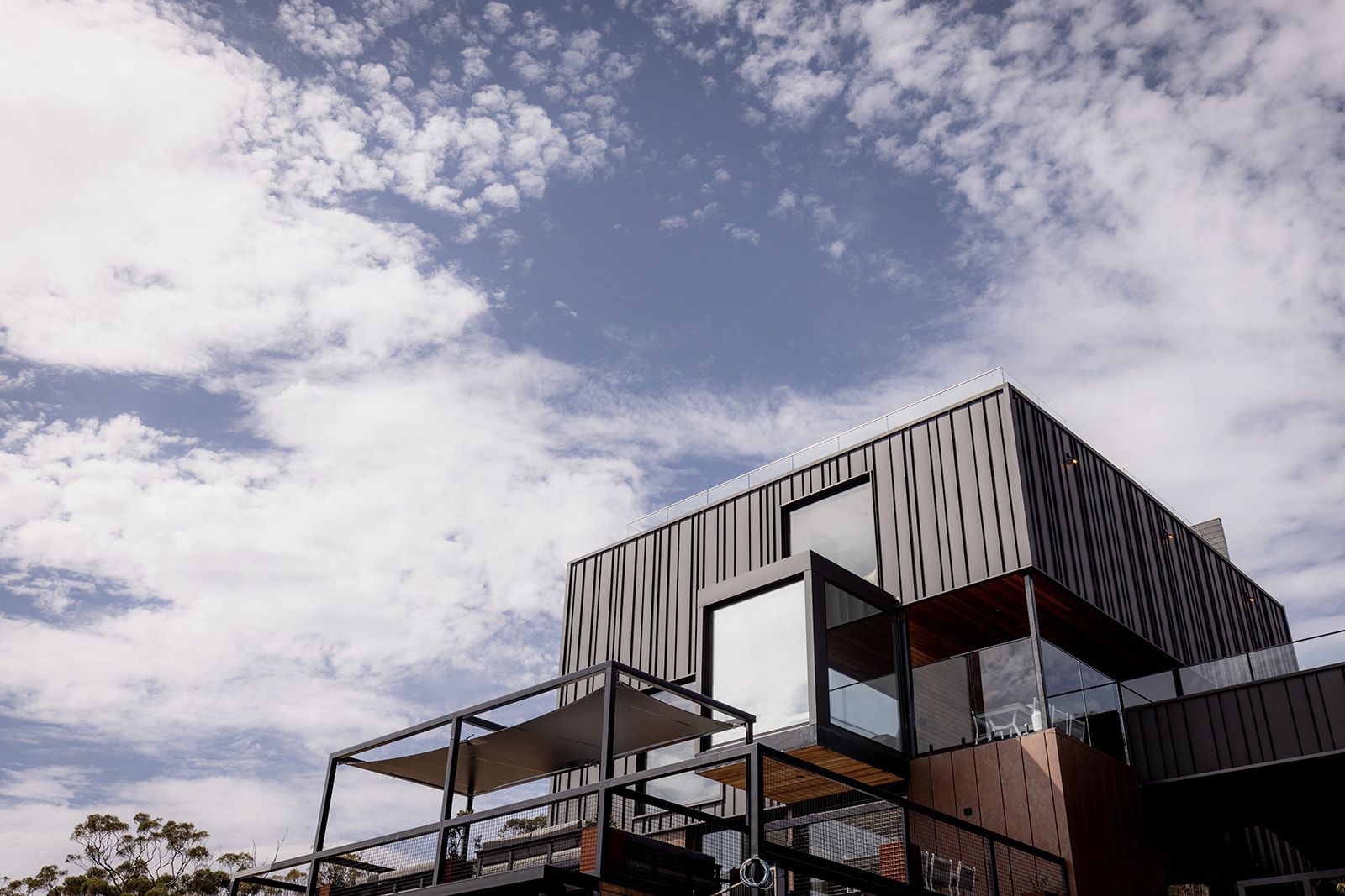 A large building with a balcony and stairs against a blue sky with clouds.