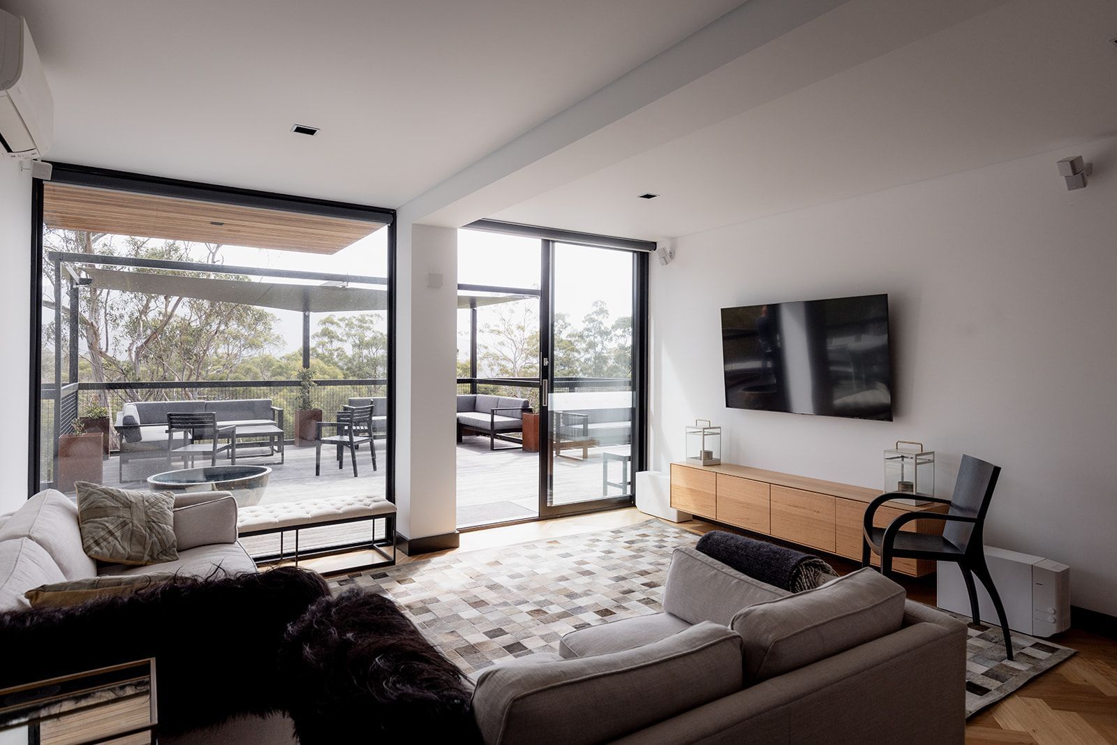 A living room with a couch , chair , television and sliding glass doors.