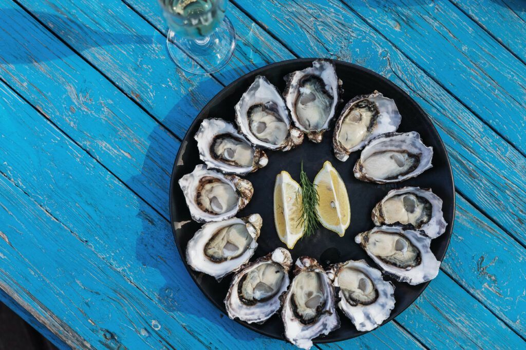 A plate of oysters on a blue wooden table.