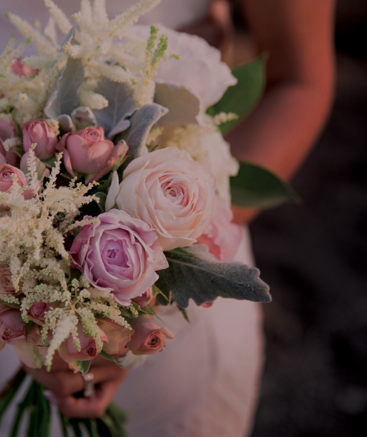 A woman in a white dress is holding a bouquet of pink and white flowers.