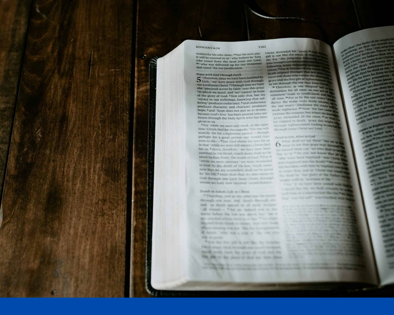 Open book on a wooden table with a blue border at the bottom.