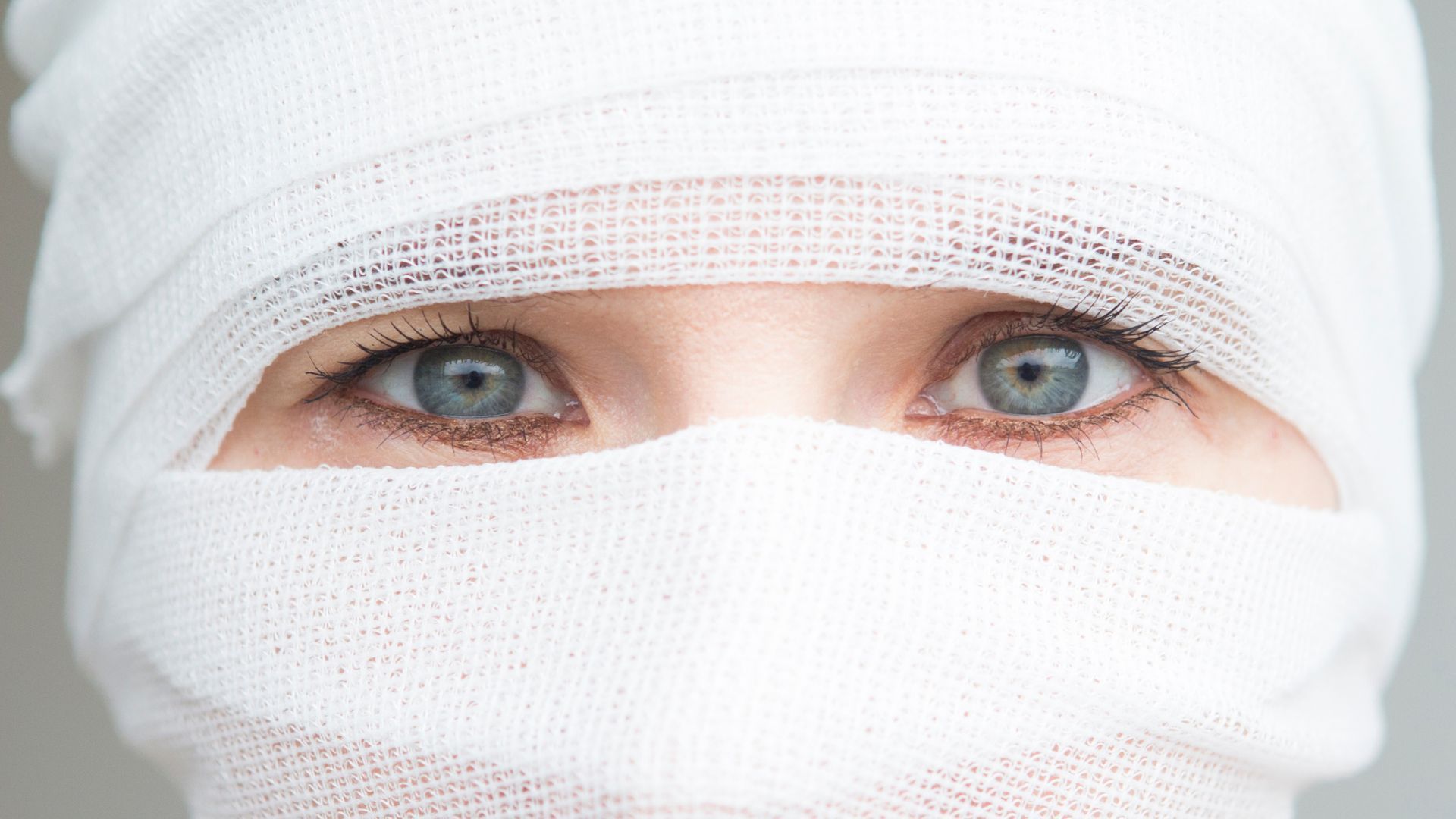 Close-up of eyes peering through white bandages covering the face