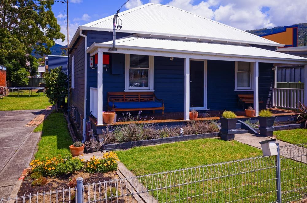 A Blue House with A White Roof and A Porch — Glen Lamberts Wall Cladding & Home Improvements in Wauchope, NSW