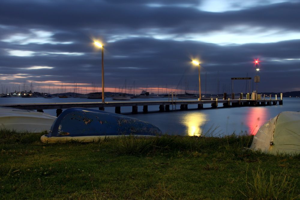 A Boat is Sitting on the Grass Near a Dock at Night — Glen Lamberts Wall Cladding & Home Improvements in Port Macquarie, NSW
