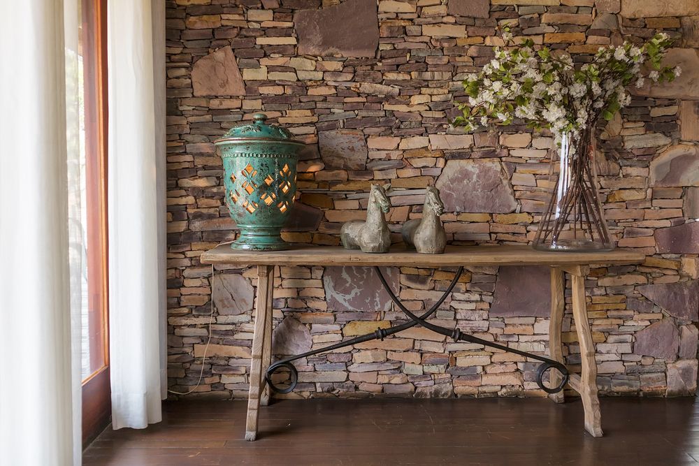 A Wooden Table With a Vase of Flowers on It in Front of a Stone Wall — Glen Lamberts Wall Cladding & Home Improvements in Lake Cathie, NSW