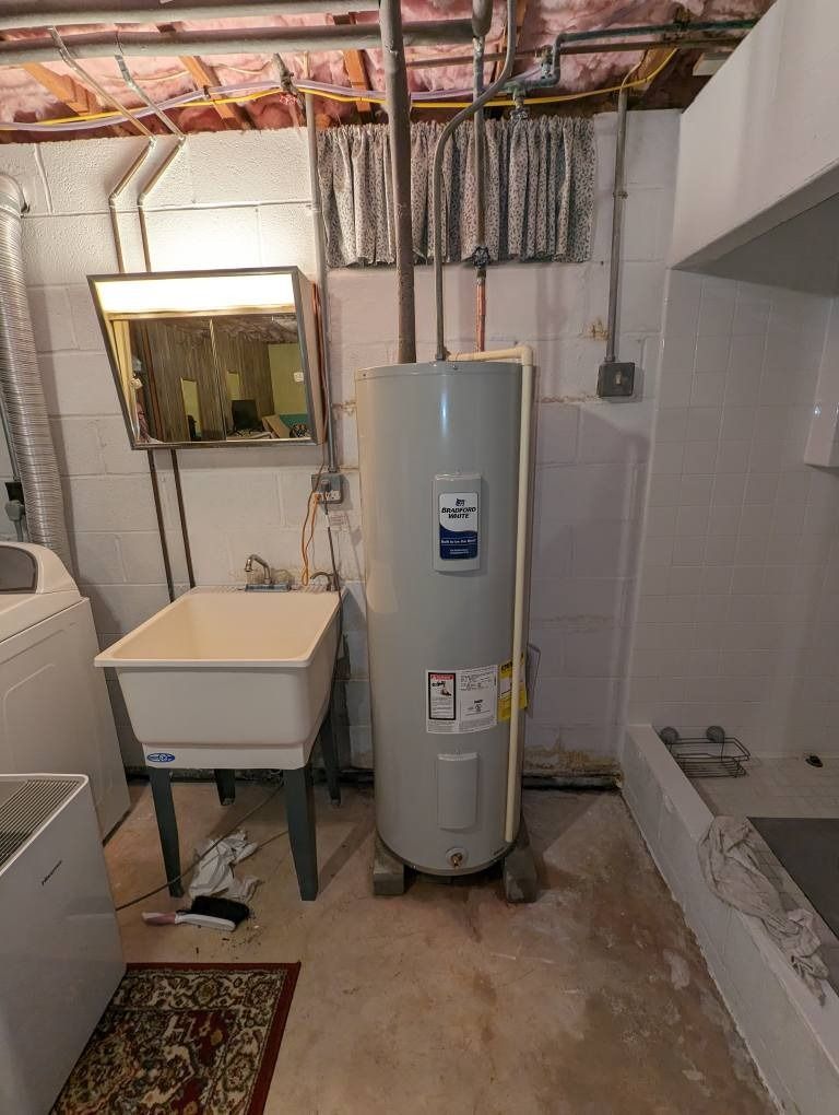 Basement utility room with water heater, laundry sink, exposed pipes, and unfinished ceiling
