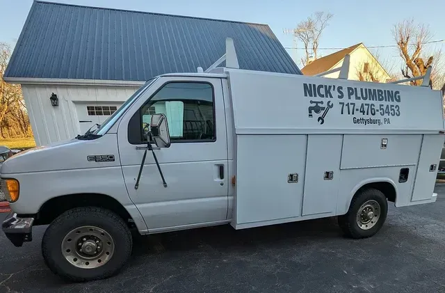 White Nick’s Plumbing service truck parked beside a house in a driveway.
