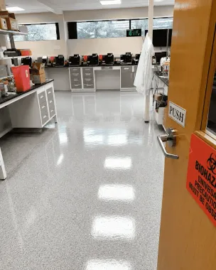 Empty science lab with counters, cabinets, and a wooden door open on the right.