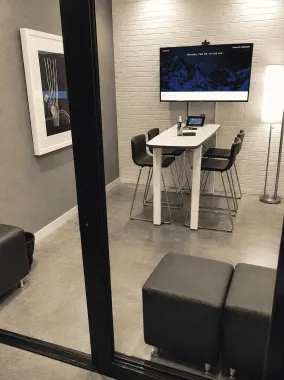 Modern office nook with a desk, monitor, chair, and gray ottoman seating.