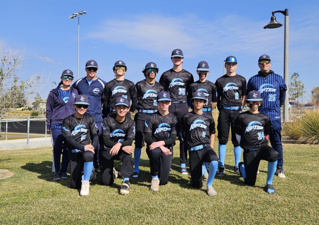 Youth baseball team posing outdoors in black-and-blue uniforms on a sunny field
