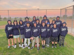 Youth sports team in navy hoodies posing on a field at sunset.