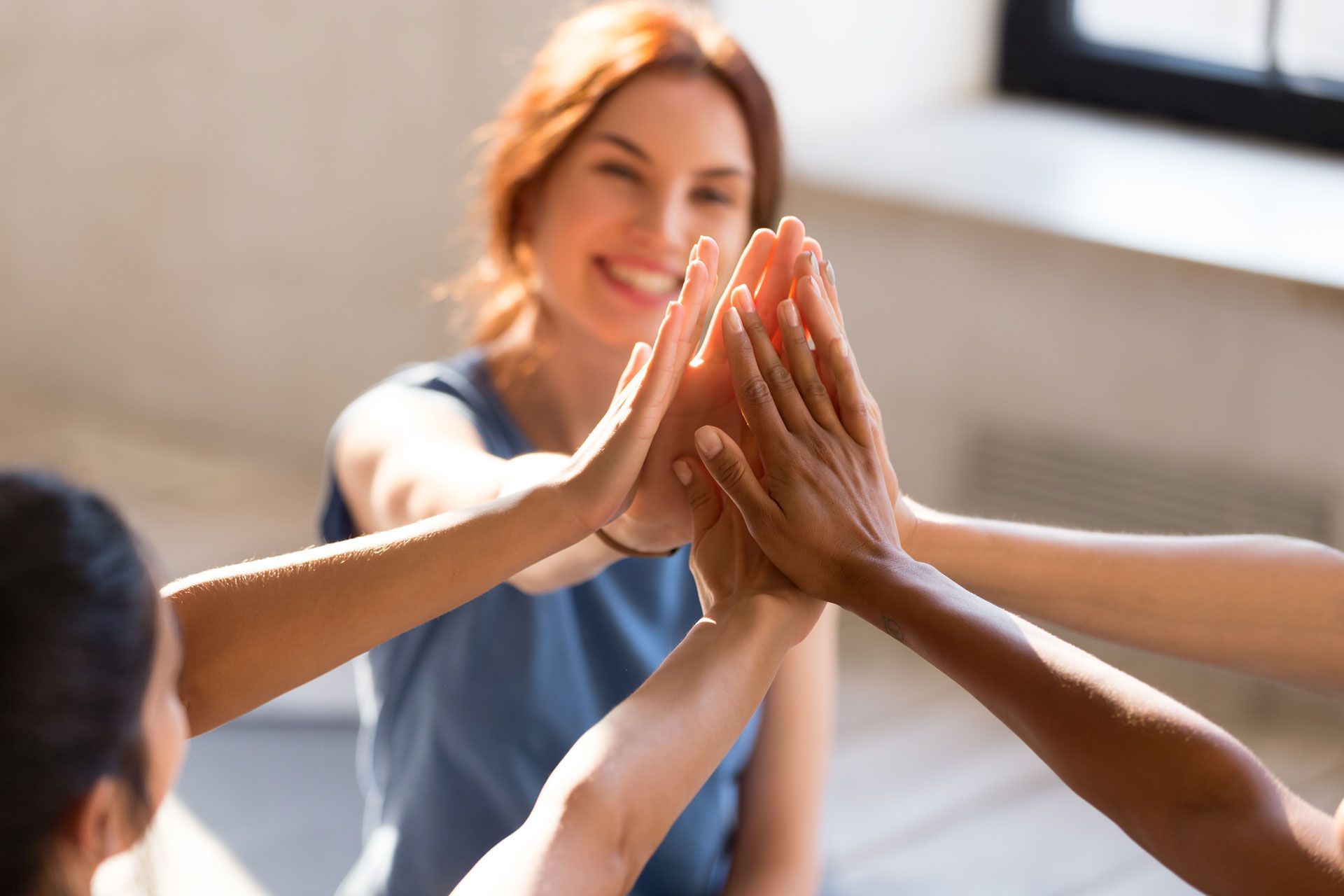Hands in a high five with a smiling woman in the background.