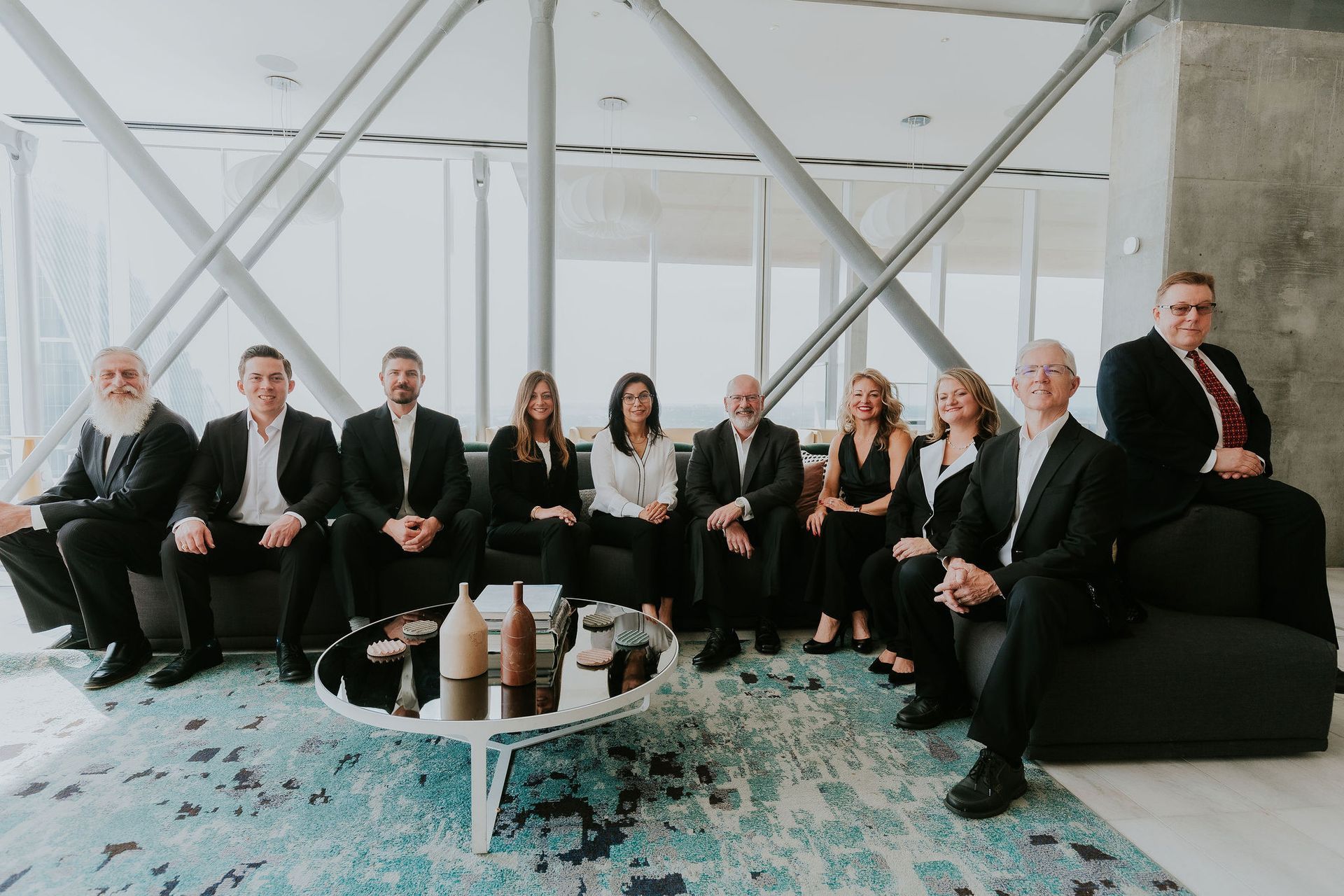 Group of people in business attire sitting on a couch in a modern office space.