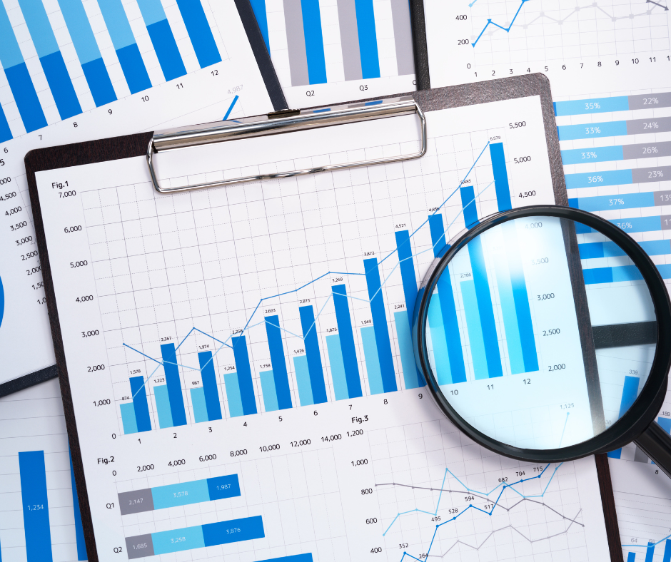 Graphs and charts with magnifying glass showing business data analysis.