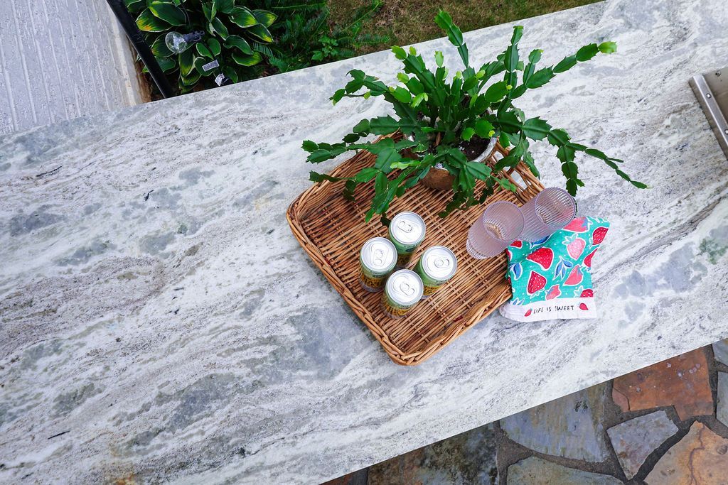 Potted plant on a stone table beside a woven tray with candles and a colorful card.