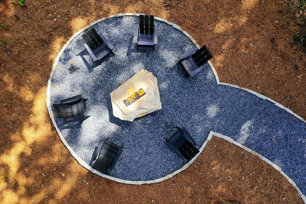 Aerial view of a blue circular outdoor table with chairs around it on dirt ground
