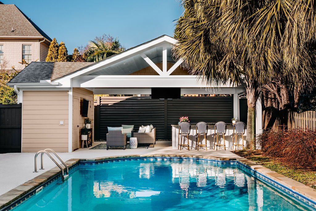 Backyard pool with a covered patio seating area and a white-roofed gazebo beside a house