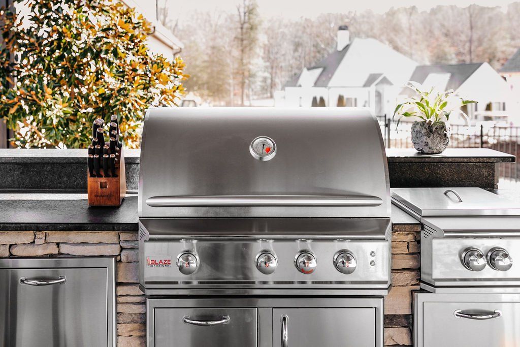 Outdoor stainless steel grill and kitchen counter with snowy backyard and houses in the background