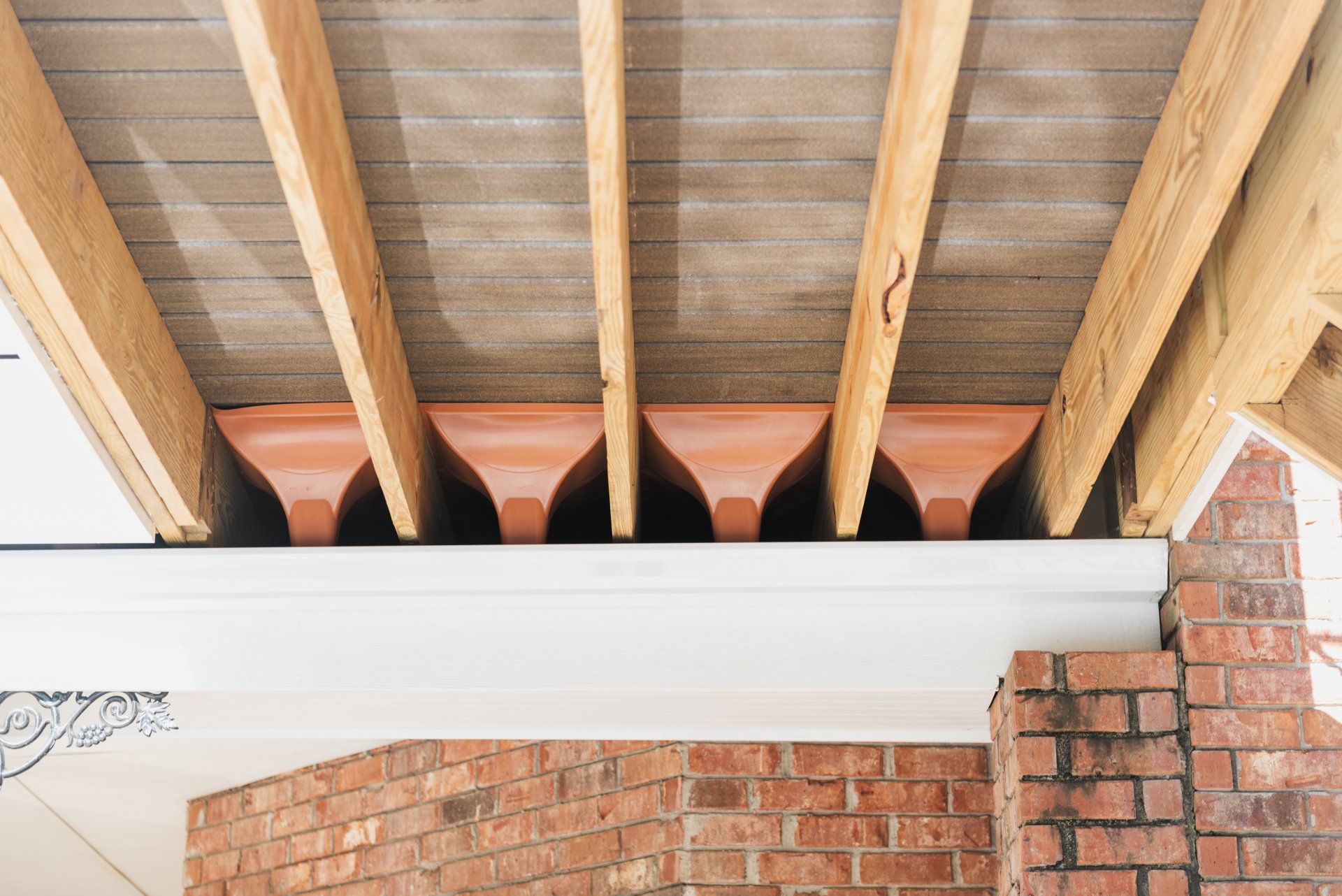 Exposed wooden roof beams above a white trim and brick wall interior
