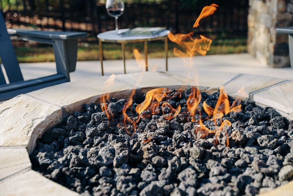 Stone fire pit with burning embers and flames outdoors on a patio